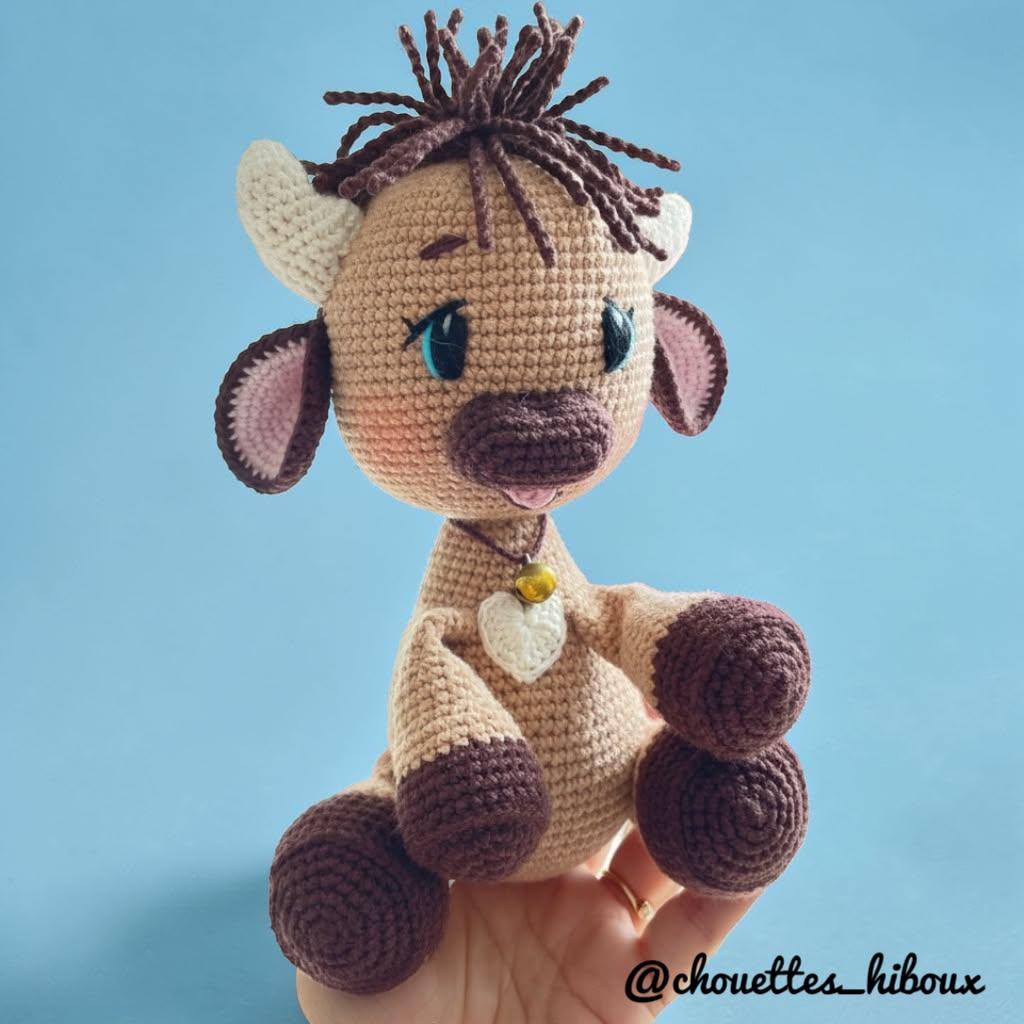 Soft beige tester-made Olly with chocolate hooves held against a blue background