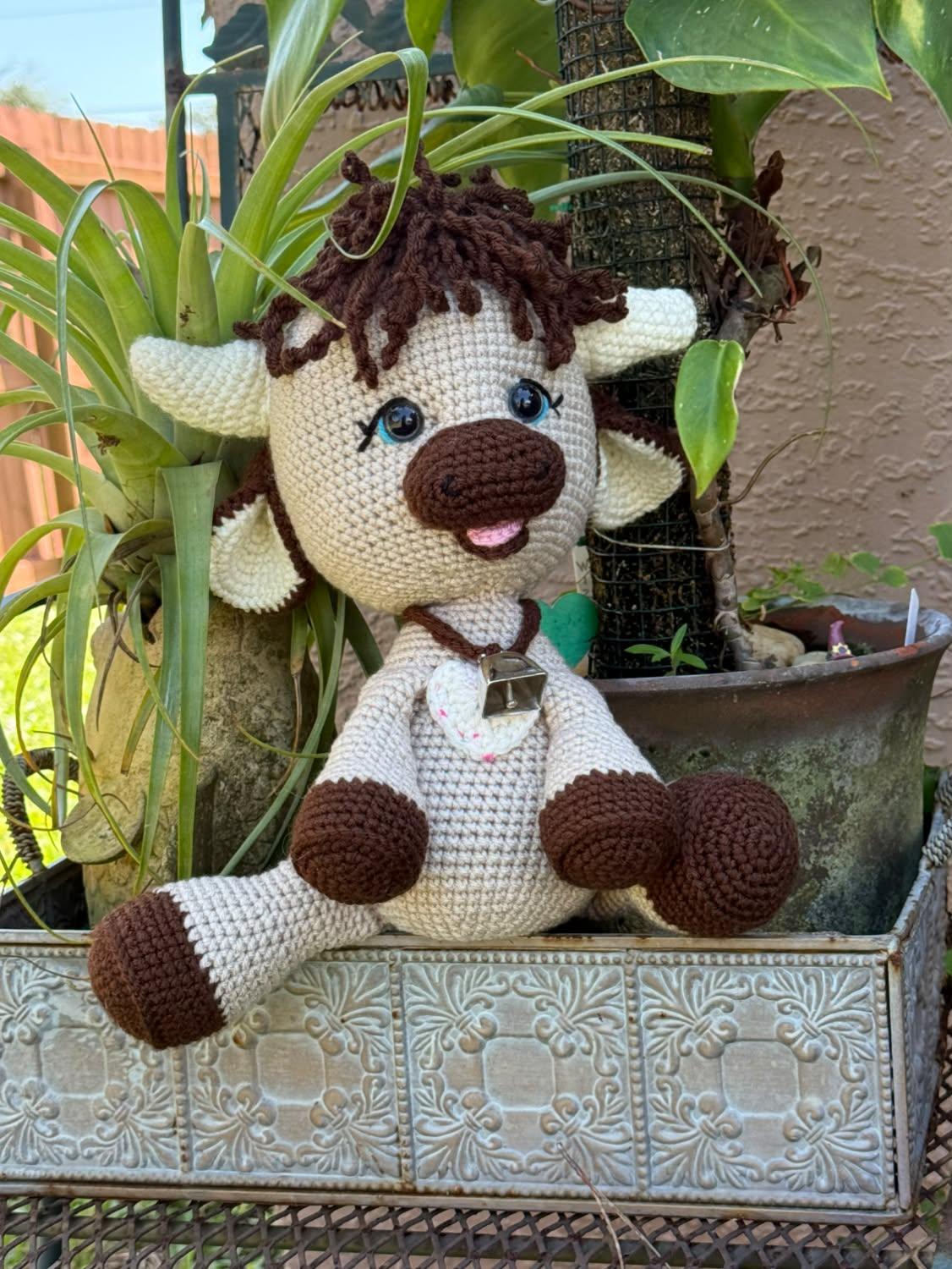 Cream and chocolate tester-made Olly sitting among leafy plants outdoors