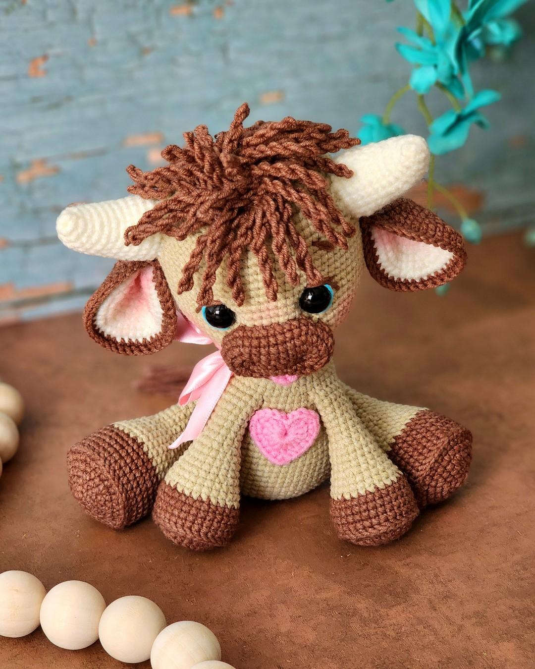 Wheat and chocolate tester-made Olly with a pink ribbon and heart sitting in a rustic studio