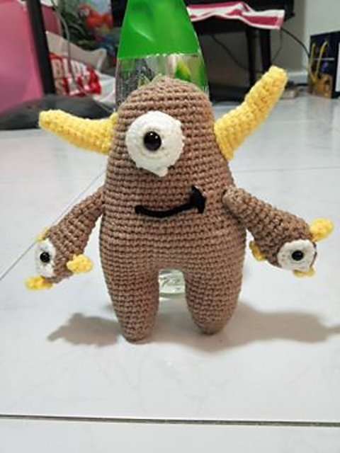Tan crochet Quill with yellow horns and tiny eye-tipped hands
